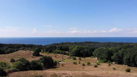 Aerial-view-of-the-coastline-of-Sejerøbugten-with-hills,-fields-and-ocean