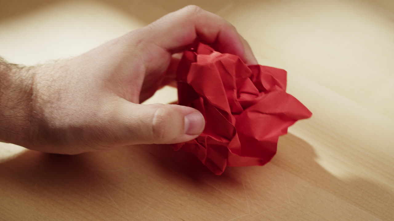 Hands crumpling red fabric on a wooden table
