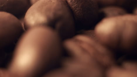 super close-up of coffee beans rolling on a brown surface
