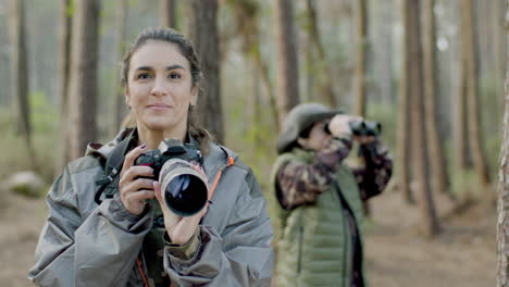 Glückliche-Frau,-Die-Fotos-Im-Wald-Macht-Und-Dann-In-Die-Kamera-Schaut