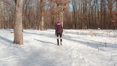 Gimbal-following-woman-walking-alone-on-snowy-winter-forest-path