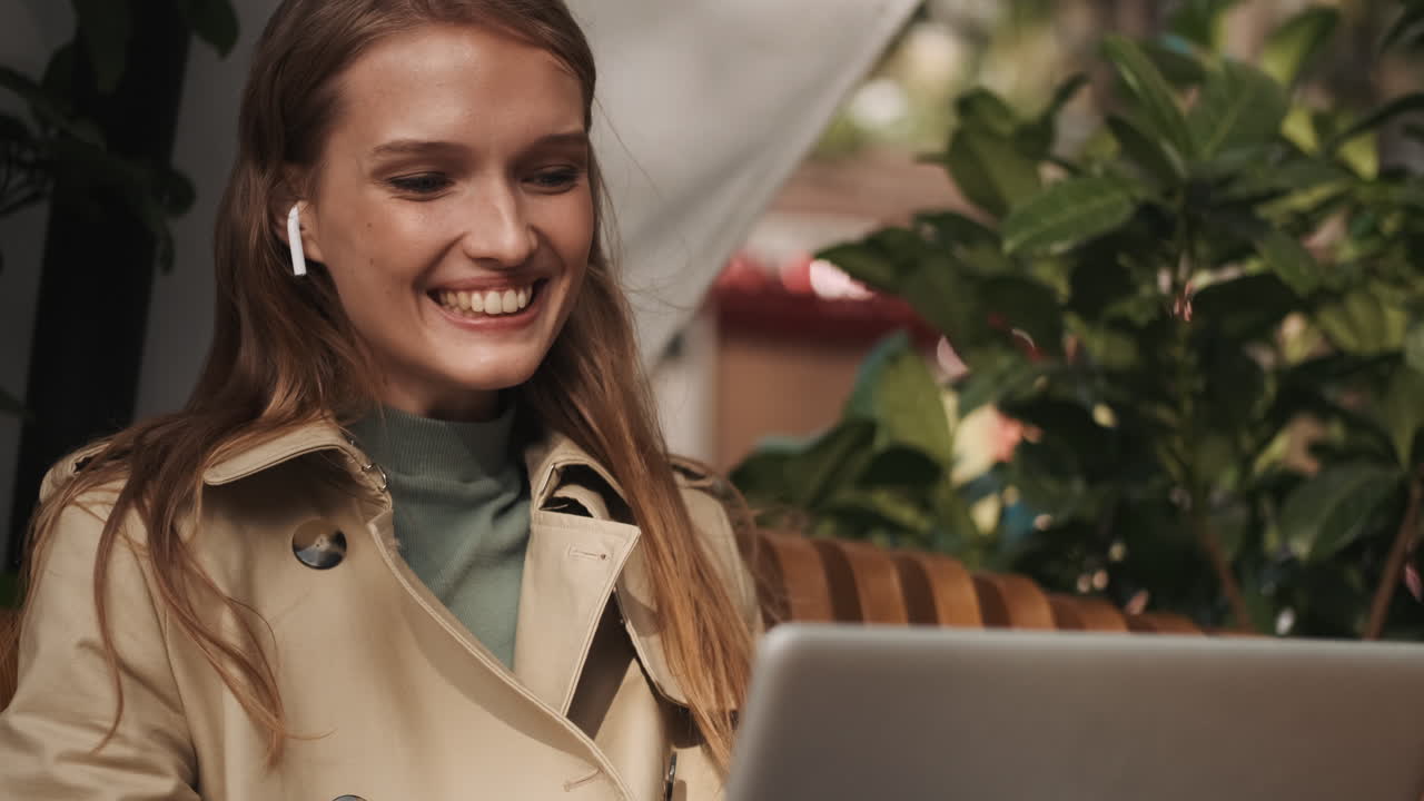 una mujer caucásica llamando por video en una computadora portátil al aire libre.