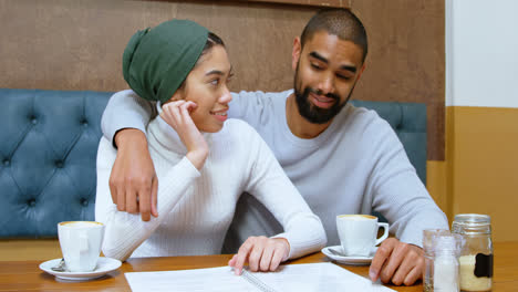 Couple-discussing-menu-card-in-cafe-4k