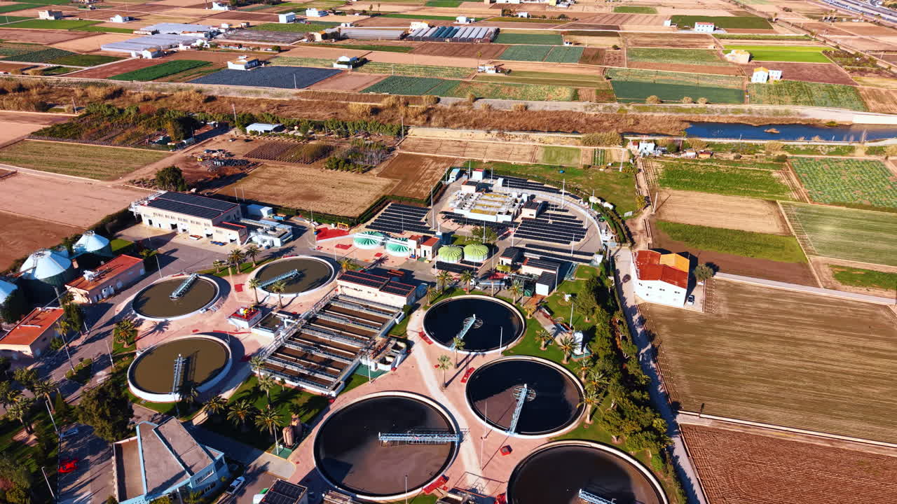 Industrial sewage treatment facility surrounded by agricultural landscape aerial. Aerial perspective of a water reclamation plant with solar arrays located next to farm fields and a river