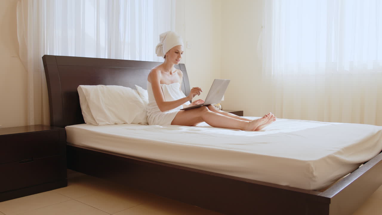 침대에 노트북으로 일하는 여자