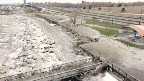 aerial drone shot descending down on dirty snow and ice along a roadside, the aftermath of what remains after a deadly winter snowstorm in buffalo new york, usa