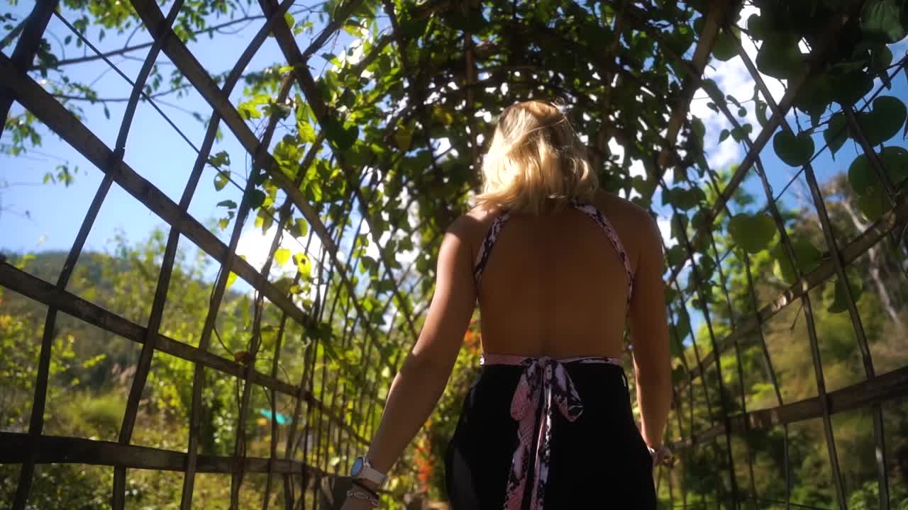 더운 여름날 태국의 관광 지역에 있는 대나무 다리에서 부드러운 엉덩이 흔들림으로 아름다운 금발 여성이 걷는다