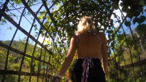 hermosa mujer rubia camina con un suave movimiento de cadera en un puente de bambú en la parte turística de tailandia en un caluroso día de verano