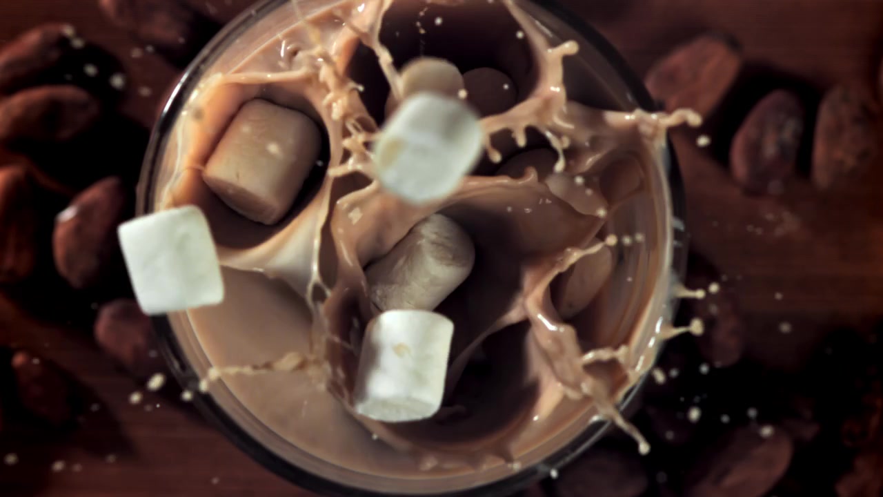 Marshmallow in movimento rallentato che si tuffano nella cioccolata calda