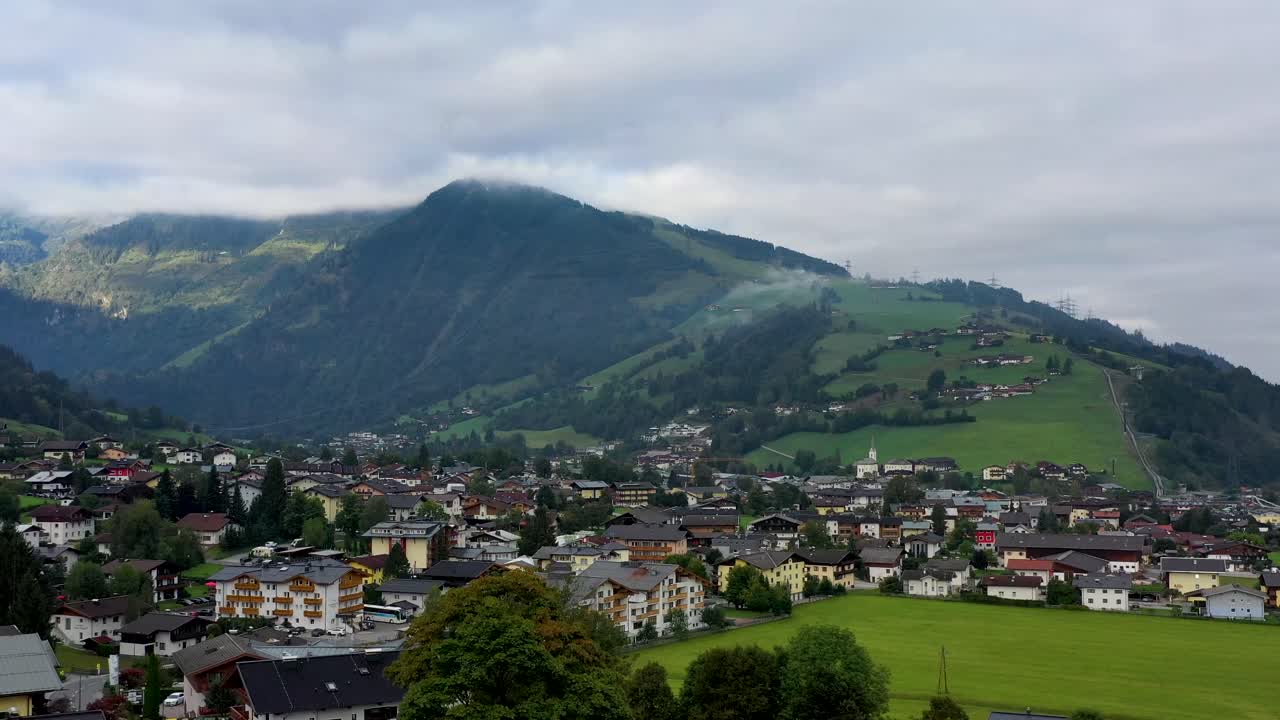 vista aérea del pueblo austriaco rodeado de montañas durante el verano, exuberantes colinas verdes y cielo azul - panorama paisajístico de los alpes desde arriba, austria, europa