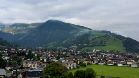 Luftaufnahme-Des-österreichischen-Dorfes-Umgeben-Von-Bergen-Im-Sommer,-üppigen-Grünen-Hügeln-Und-Blauem-Himmel---Landschaftspanorama-Der-Alpen-Von-Oben,-österreich,-Europa