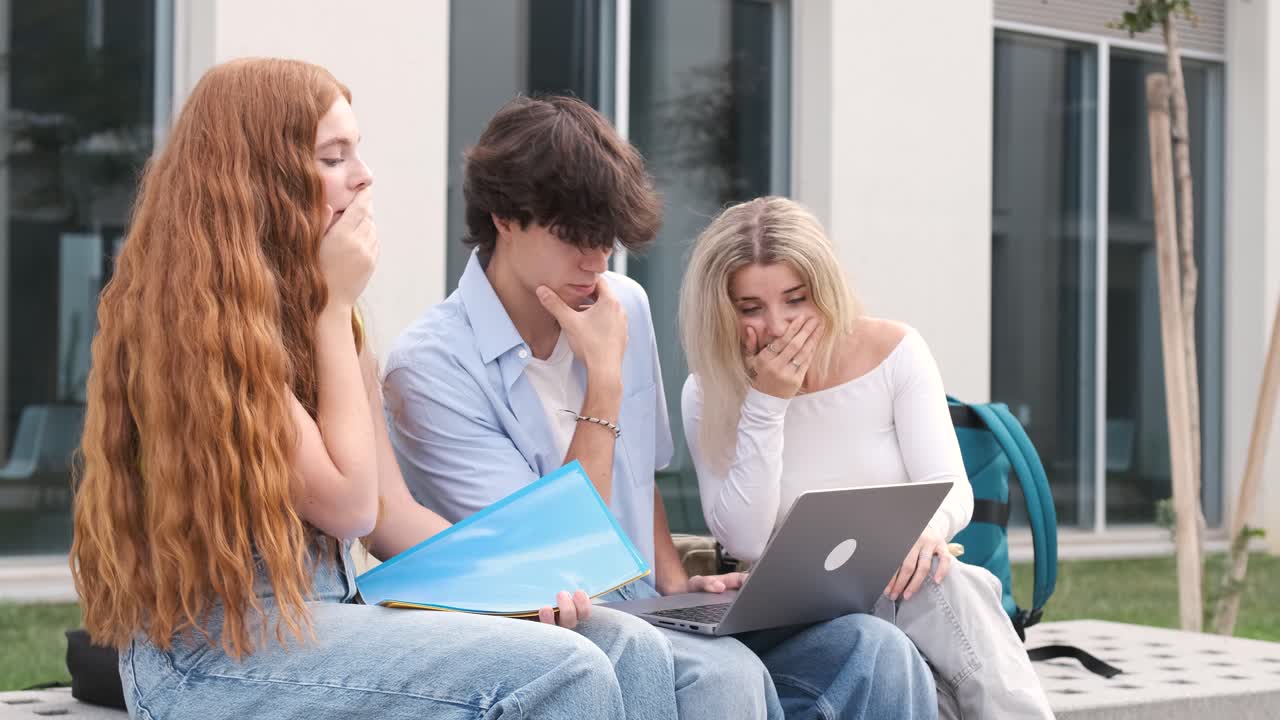 Upset friends checking exam results on laptop outside university building