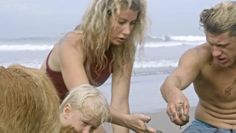 parents helping little son with building sand castle on beach