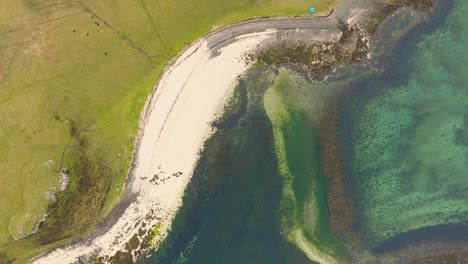 aerial drone shot of coral beach on the isle of skye, scotland, with turquoise waters, white sand, and surrounding green hills creating a stunning coastal landscape