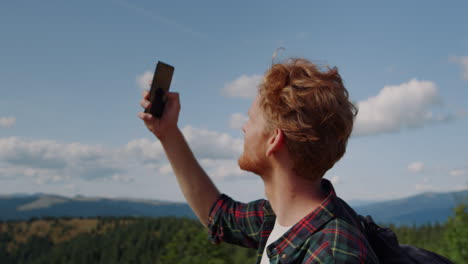 Hiker-holding-smartphone-in-hand-on-top-of-mountain