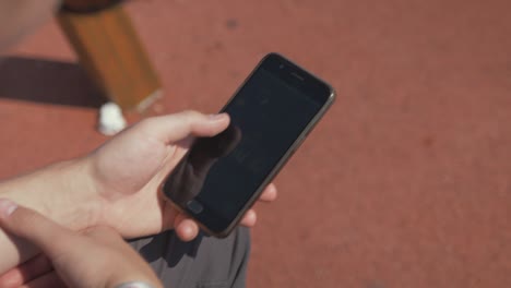 young man browsing social media on phone in playground summertime