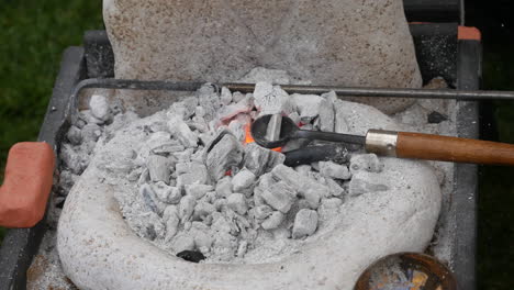 detailed view of a blacksmith's forge with fiery coals melting metals and tongs, depicting the art of metalworking