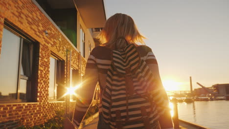 an active woman runs skipping along the embankment the setting sun is reflected in the windows of th