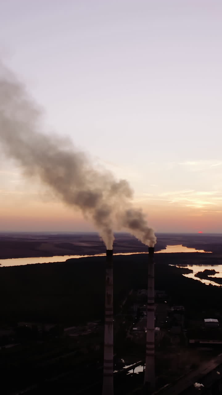 Industrial factory in nature in the evening. Chemical smoke from the factory chimneys. Concept of environmental pollution. Vertical video