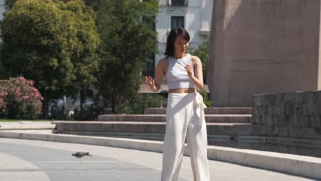 woman performing dance on footpath in city park during sunny day