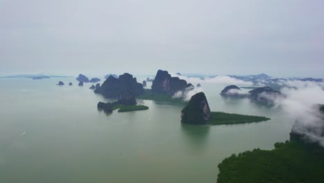 aerial views across phang nga bay in thailand with limestone islands and mangrove forests covered with low clouds