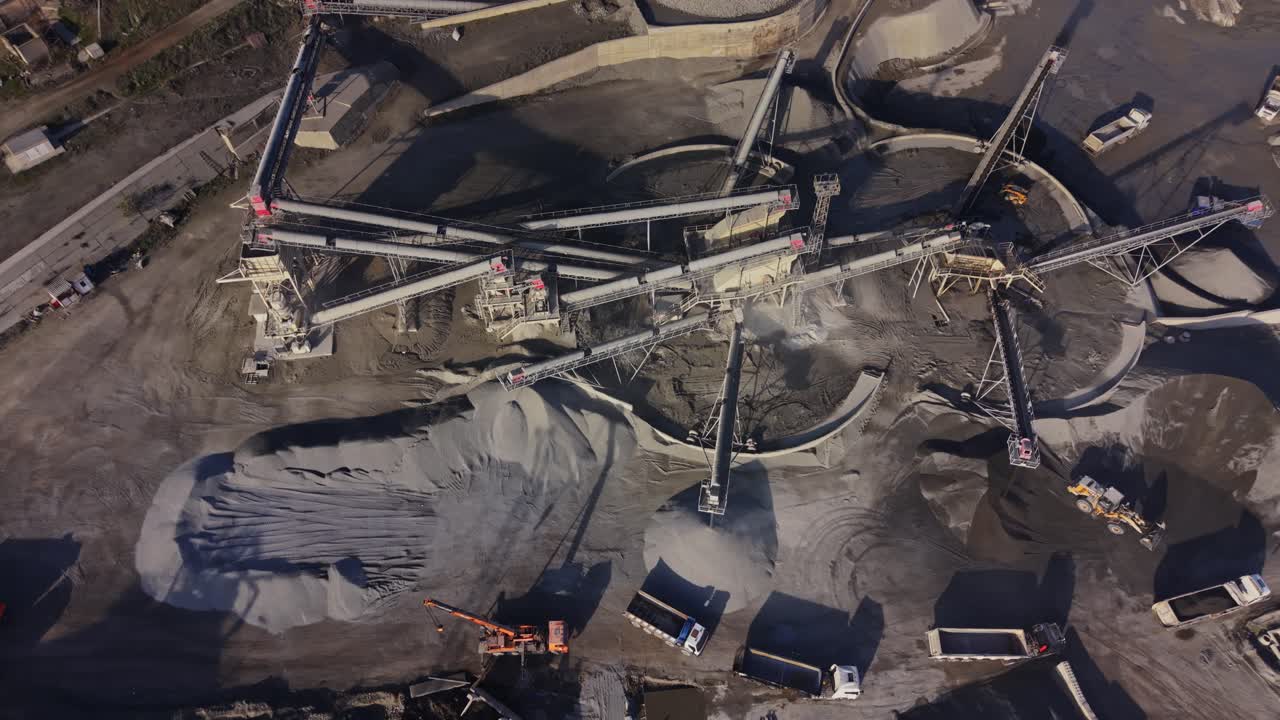 Heavy machinery operates at a large quarry site near a mine
