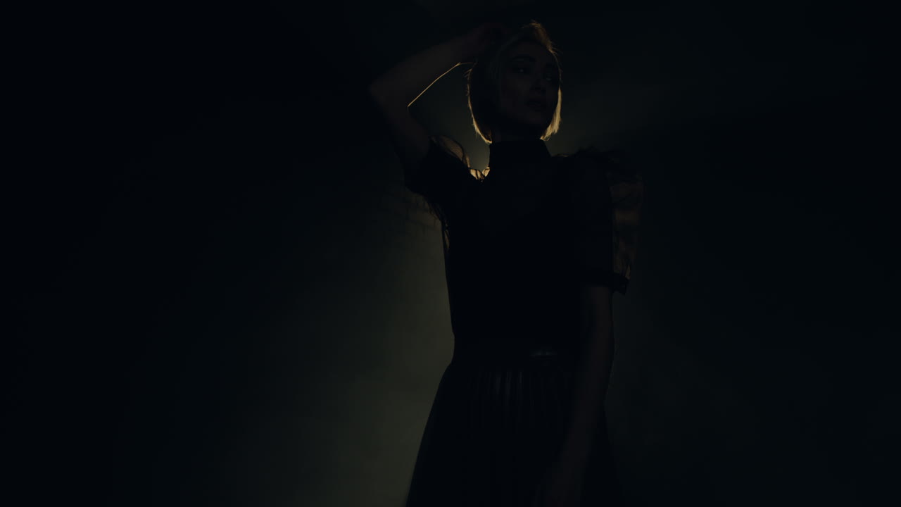 художественная фотосессия в темной студии с одним источником света, освещающим силуэт модели, меняющей позы