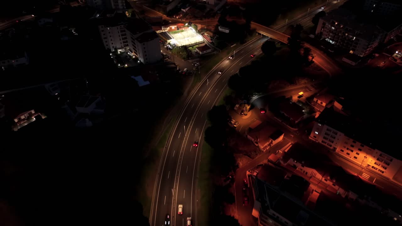 Aerial view curved highway with cars and buildings at night in urban city
