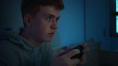 focus caucasian teenage boy playing on game controller at night