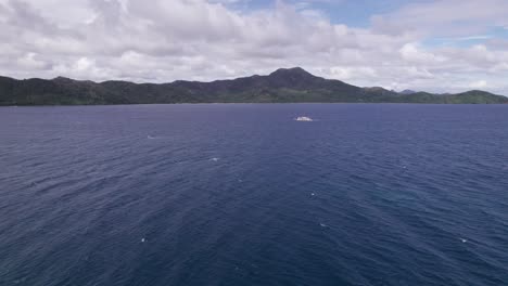 Aerial View of Solitary Boat Sailing in Blue Sea by Coastline of Tropical Island, Drone Shot