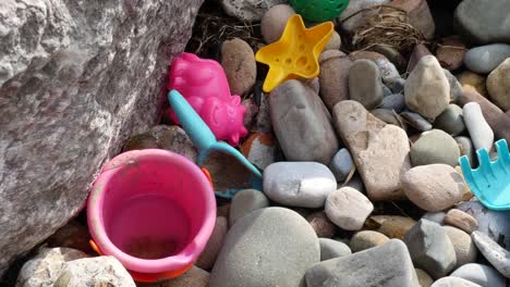 Von-Oben-Nach-Unten-über-Stein-Kiesstrand-Ausrangiert-Kinder-Bunter-Eimer-Und-Spielzeug-Verschmutzung