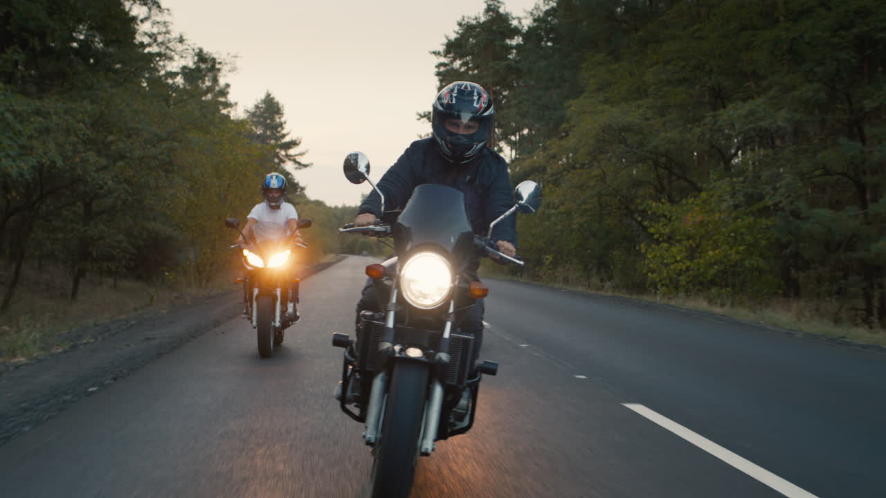 los ciclistas recorren la carretera entre el bosque de pinos