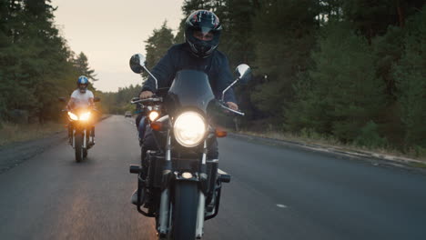 bikers ride on the road among the pine forest