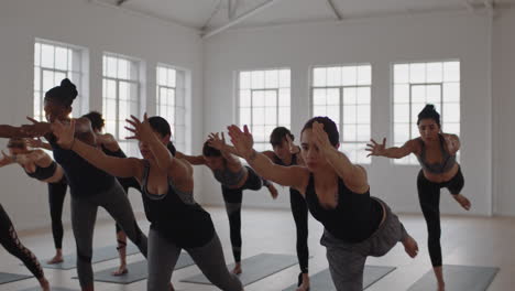 Clase-De-Yoga-Grupo-De-Mujeres-Multirraciales-Practicando-Pose-Guerrera-Disfrutando-De-Un-Estilo-De-Vida-Saludable-Haciendo-Ejercicio-En-El-Gimnasio-Instructor-Enseñando-Meditación-Grupal-Al-Amanecer