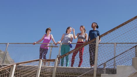 grupo multiétnico de mujeres hablando en un puente en la playa y el fondo del cielo azul