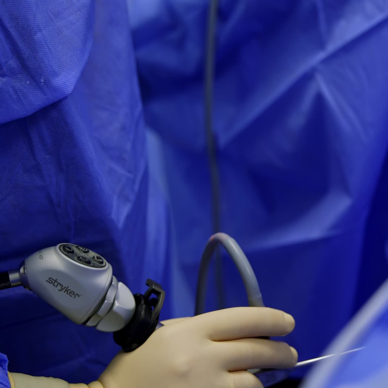 Electric tool device in the hands of a surgeon. Doctor applies instrument slowly and carefully moving it. Close up. Vertical view