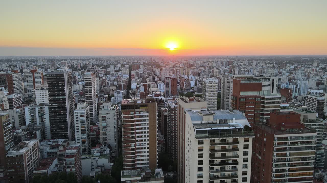 dolly volando sobre los edificios de la ciudad de buenos aires al atardecer con un sol brillante en el horizonte, argentina