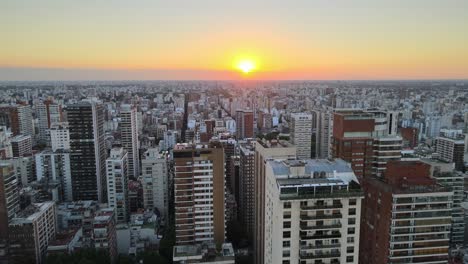 dolly in flying over buenos aires city buildings at sunset with bright sun in horizon, argentina