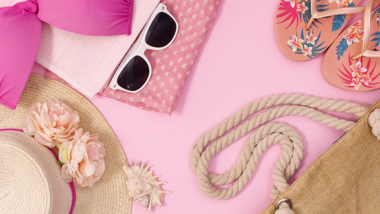 accesorios de moda de verano para la playa y las vacaciones se mueven sobre un fondo rosa pastel.