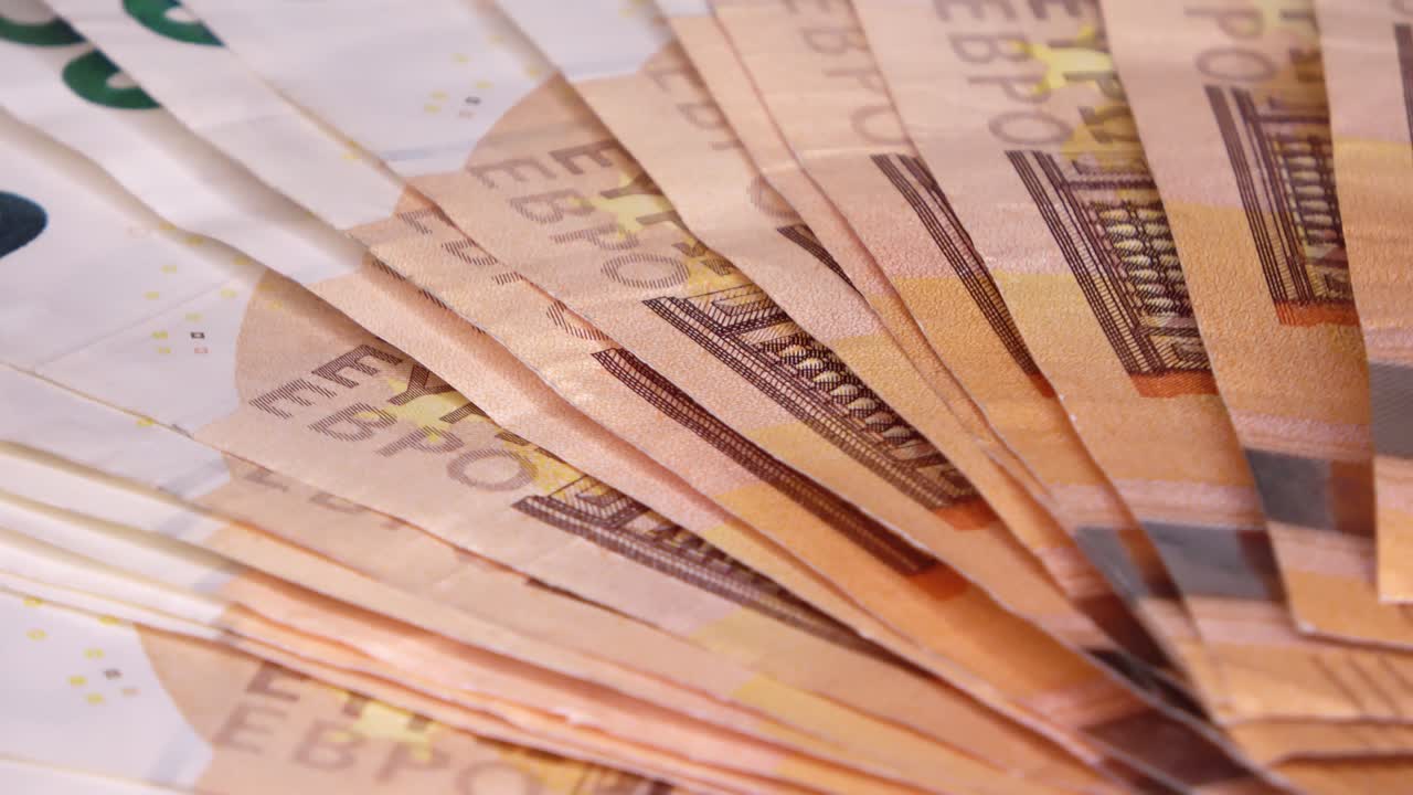 Nahaufnahme in Endlosschleife von zahlreichen 50-Euro-Banknoten, die übereinander auf einem sich drehenden Teller liegen.
