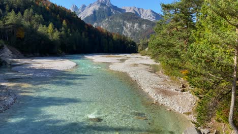 blue isar valley with isar river in the near of scharnitz in austria with trees and high karwendel mountains in the background