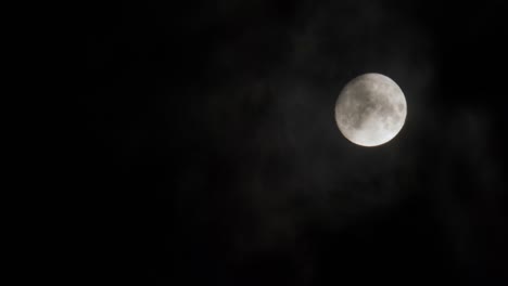 luna envuelta por nubes contra un cielo oscuro, evocando el misterio y la belleza del cosmos
