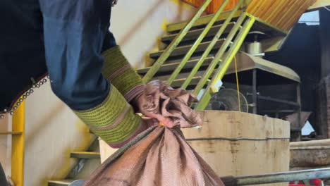an asian man is tying a sack.