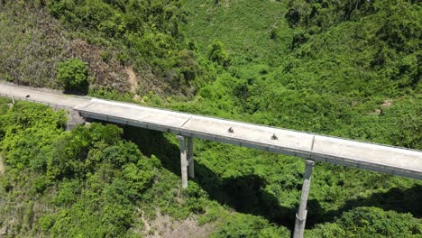 el dron que se mueve hacia atrás revela un puente con dos motocicletas en marcha