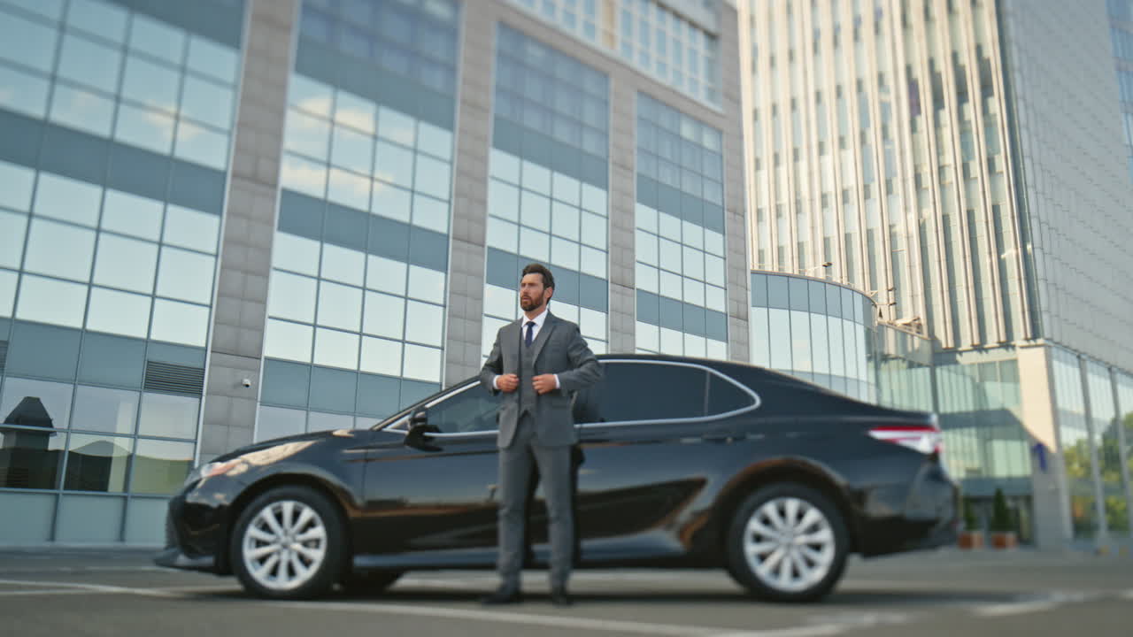 hombre de negocios exitoso esperando coche ajustando traje. orgulloso dueño de la compañía posando