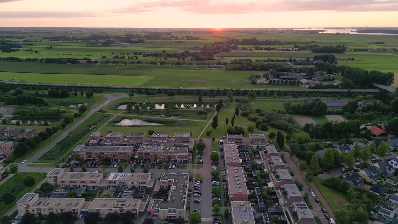 fotografía de un avión no tripulado de una zona residencial de la ciudad de nijkerk en los países bajos con un parque natural, una carretera y campos verdes al atardecer