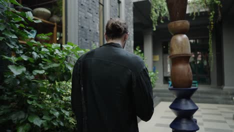 man walking through a modern courtyard with an abstract sculpture