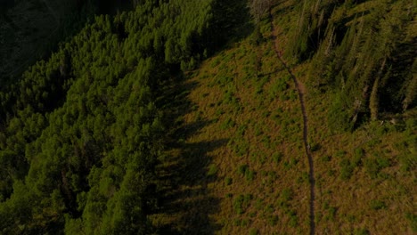 Antena-Sobre-La-Cordillera-De-Travesía-Mientras-Dos-Ciclistas-Andan-En-Bicicleta-Por-El-Sendero-Al-Atardecer