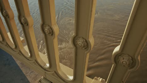 close-up of ornate bridge railing over flowing river