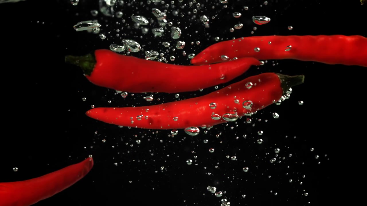 Red Chili Peppers Floating in Water with Bubbles on Black Background